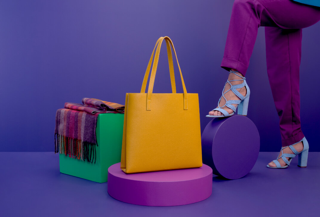 Purple scarf and yellow purse displayed with a person wearing blue high heel shoes