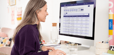 A woman sits at a desk on her computer looking at a Kijiji advertising webpage